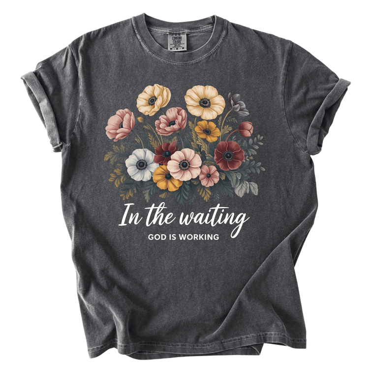 A gray t-shirt with a floral design and the text "In the waiting, God is working" printed on it.
