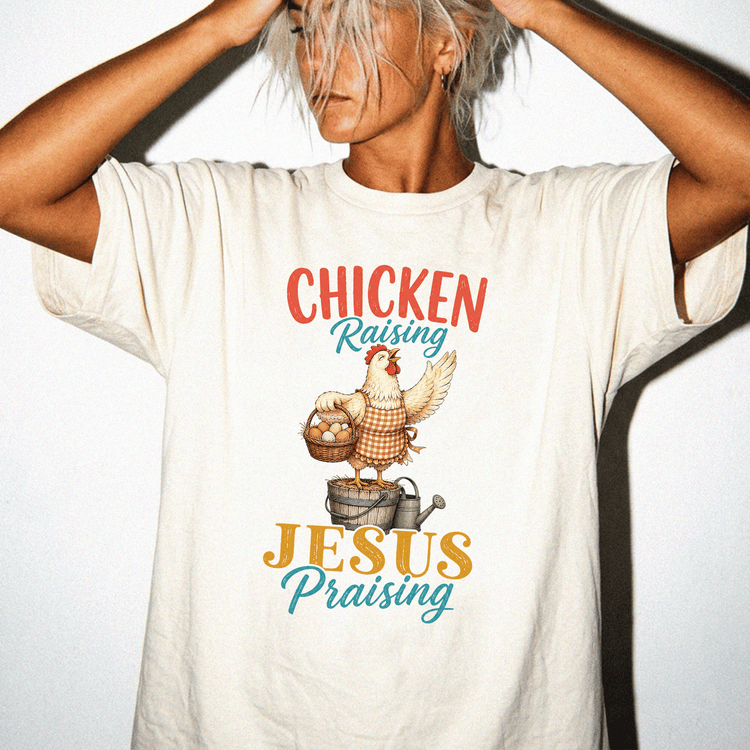 A person wearing a white t-shirt with a graphic design of a chicken and the text "CHICKEN RAISING JESUS PRAISING" printed on it.