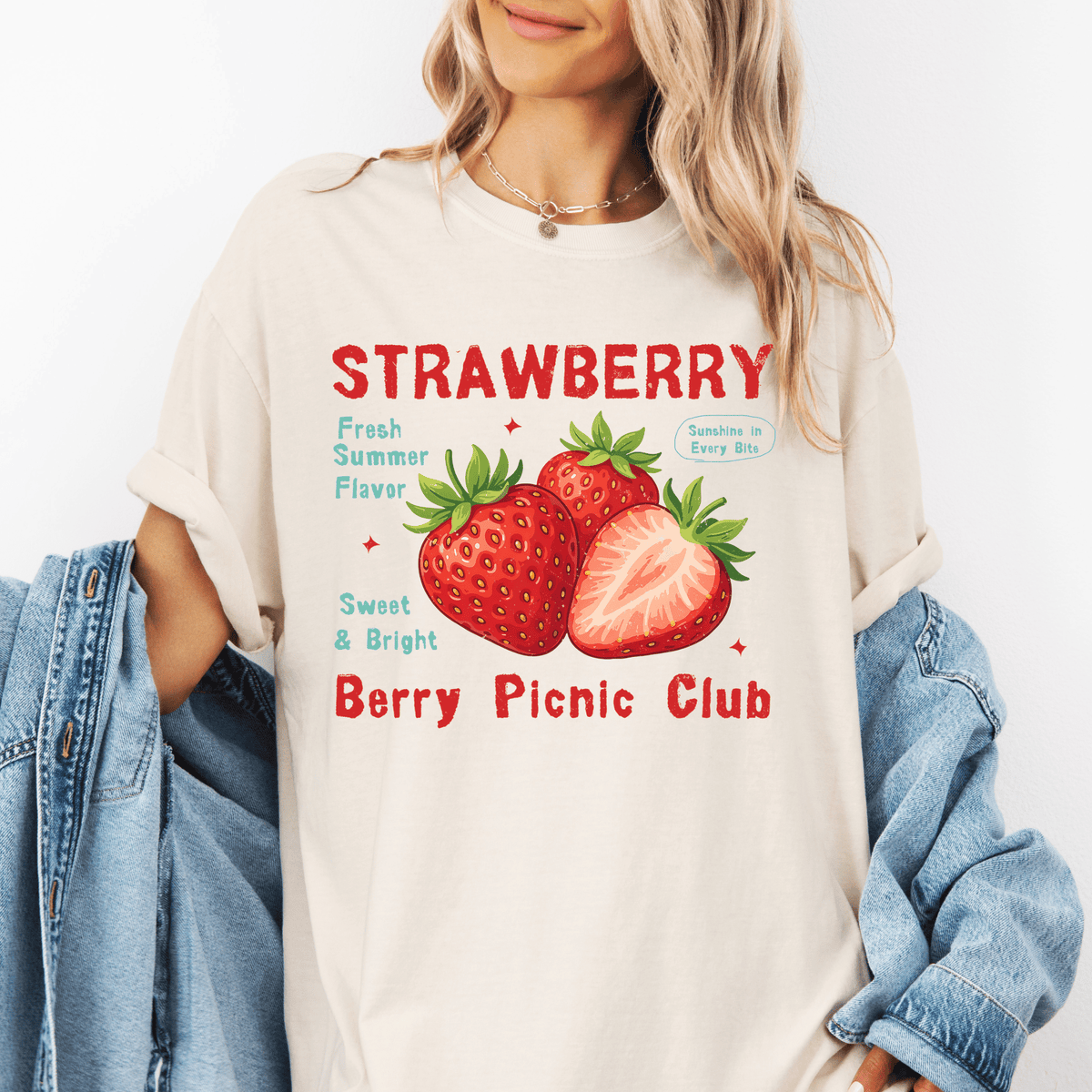 A woman wearing a white t-shirt with a graphic design of strawberries and text promoting a berry picnic club.