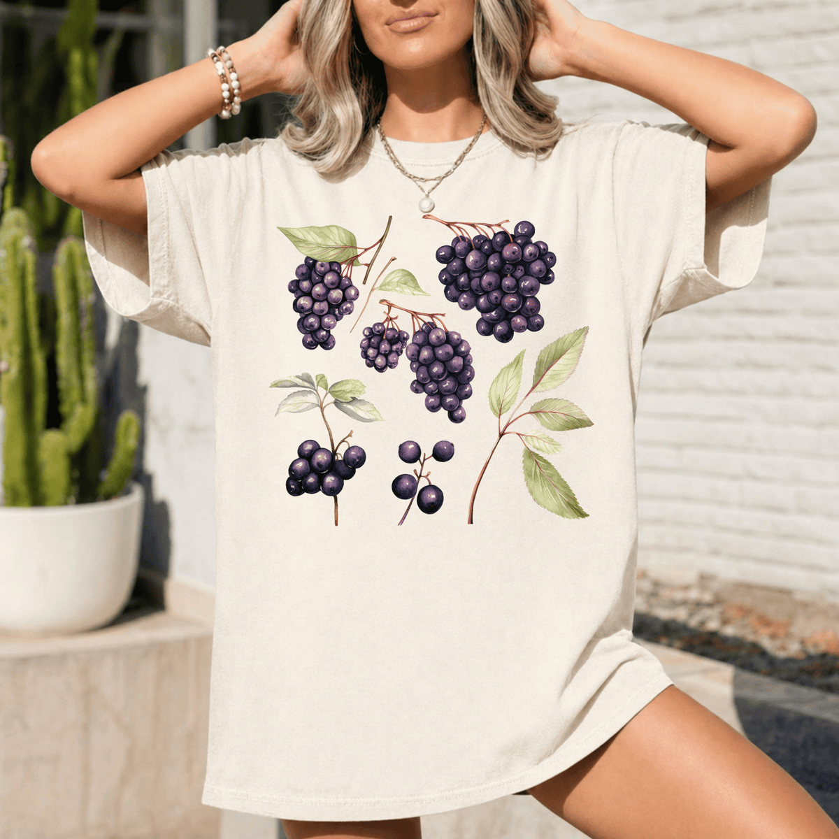 A woman wearing a white t-shirt with a graphic design of purple grapes and leaves.