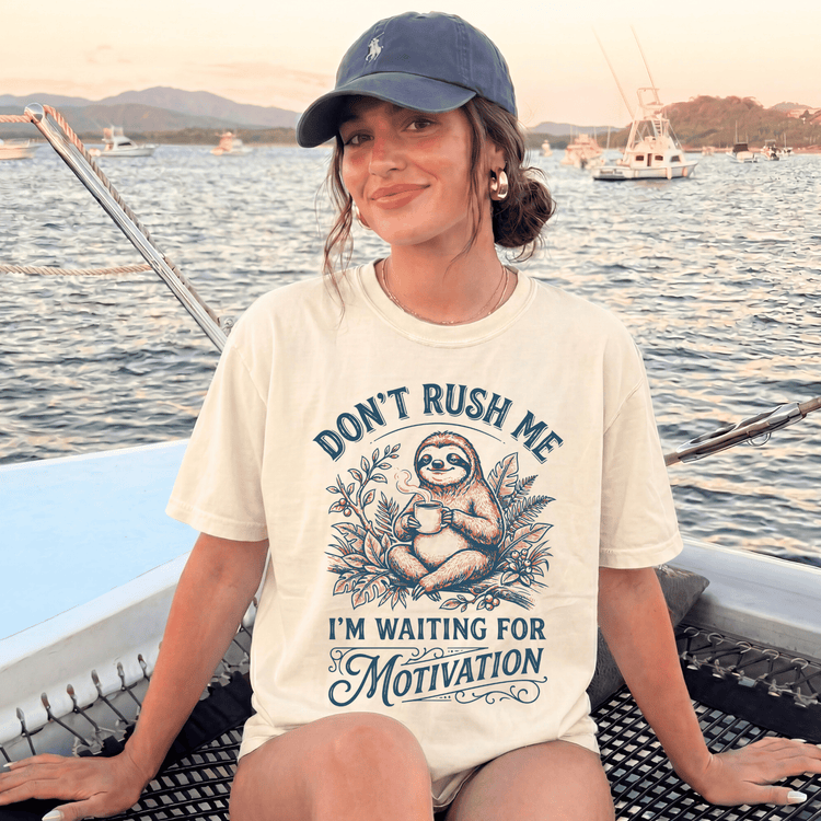 A woman wearing a white t-shirt with a graphic design and text, sitting on a boat in the water.