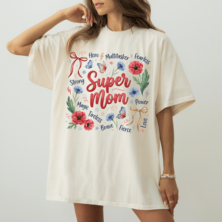 A woman wearing a white t-shirt with a colorful graphic design that says "Super Mom" surrounded by various words and illustrations.