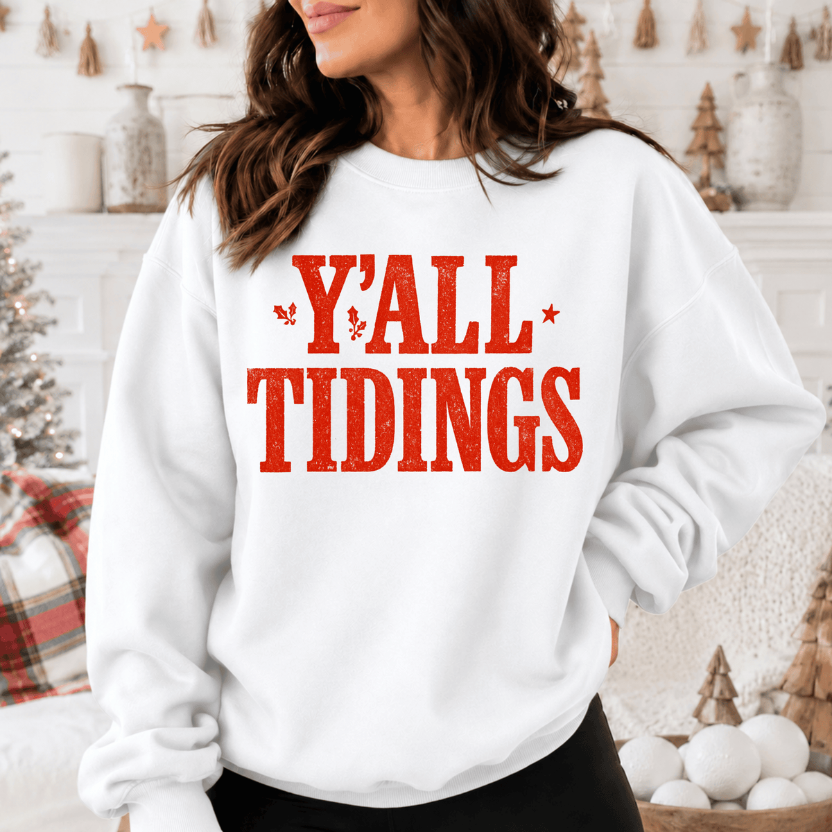 A woman wearing a white sweatshirt with the text "Y'ALL TIDINGS" printed on it.