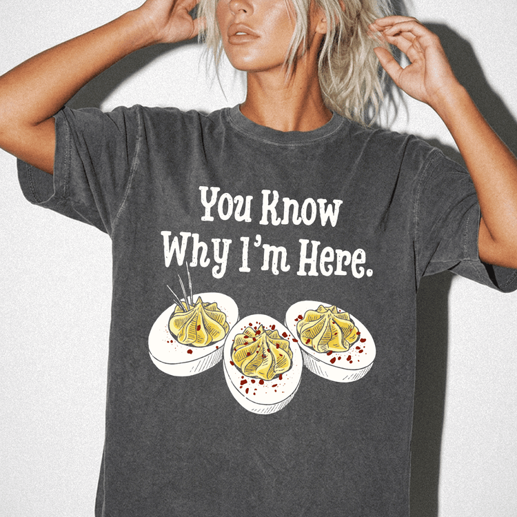 A woman wearing a gray t-shirt with a humorous text and three illustrations of deviled eggs.
