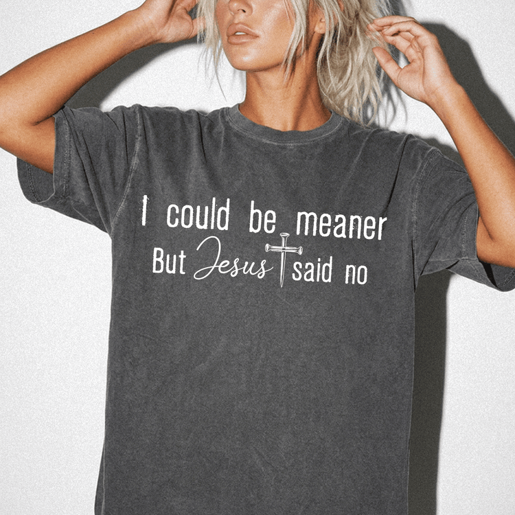A woman wearing a gray t-shirt with the text "I could be meaner but Jesus said no" printed on it.