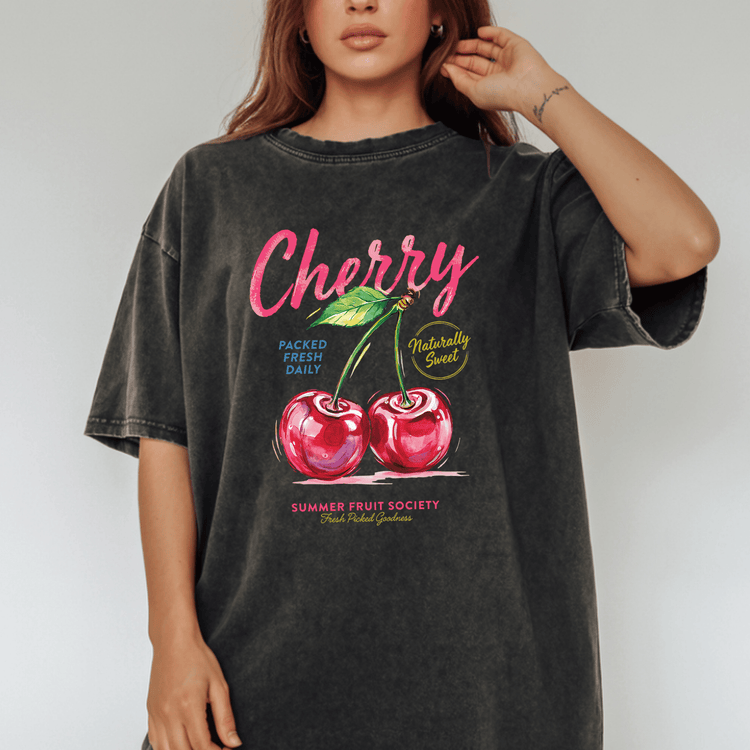 A woman wearing a black t-shirt with a graphic design of two cherries and text related to fruit.
