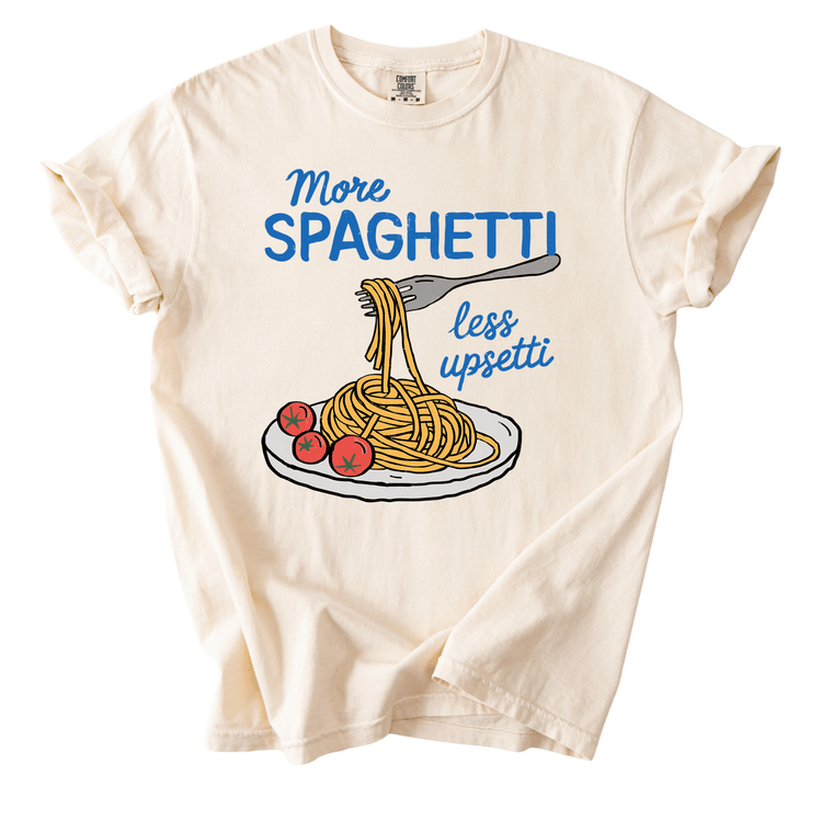 A white t-shirt with a graphic design depicting a plate of spaghetti with a fork and tomatoes. The text on the t-shirt reads "More spaghetti less upseti".