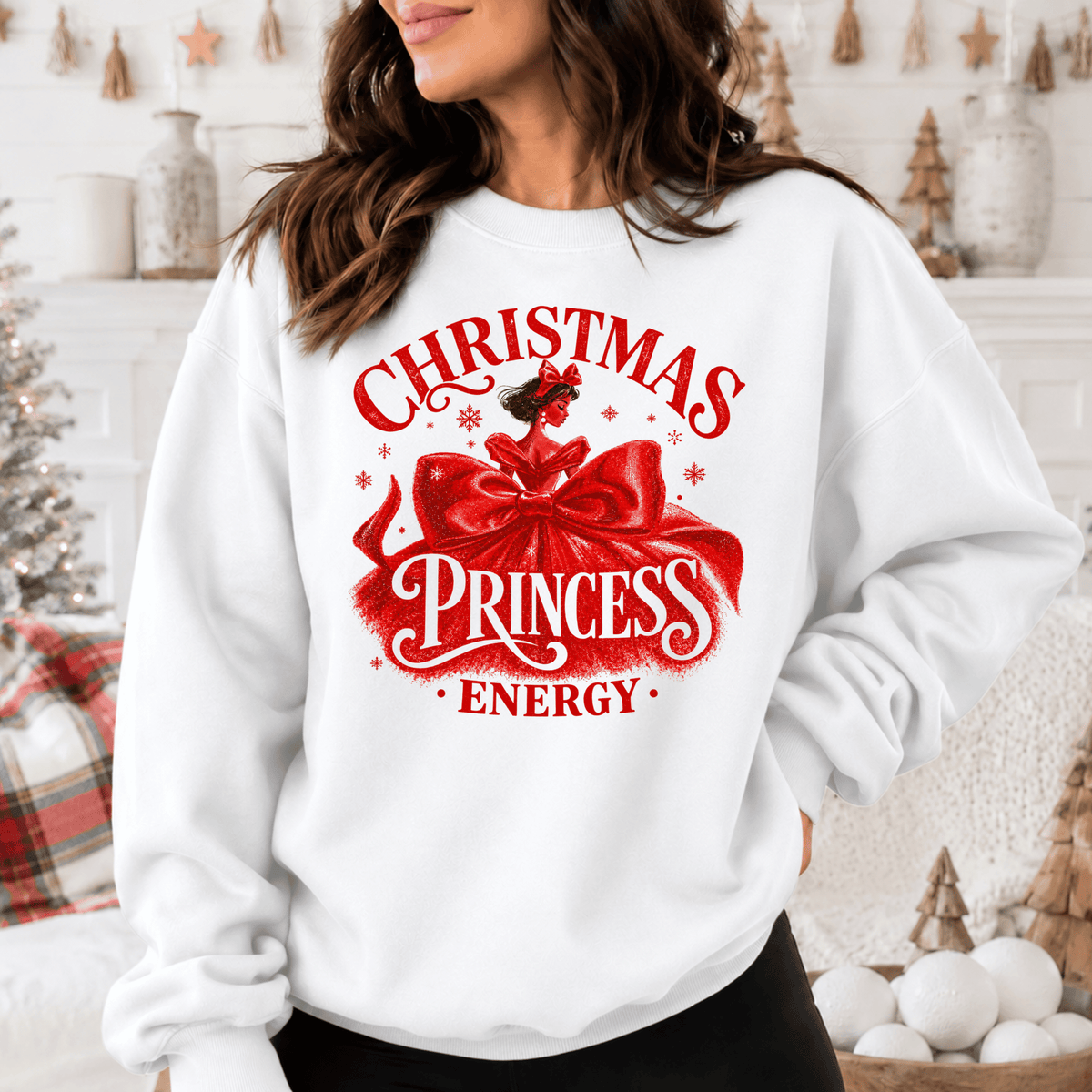A woman wearing a white sweatshirt with a red graphic design that says "Christmas Princess Energy".