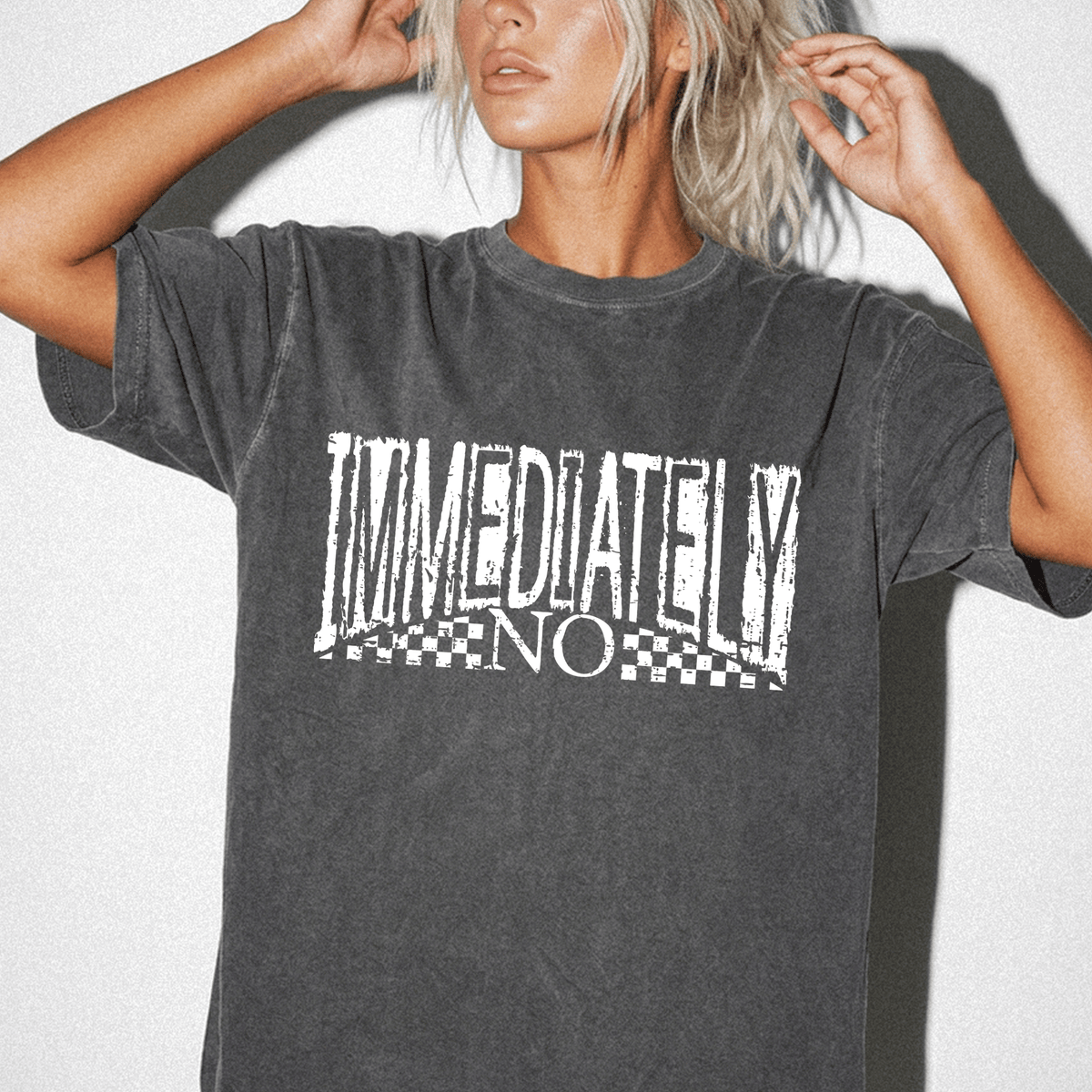 A woman wearing a gray t-shirt with the text "IMMEDIATELY NO" printed on it.