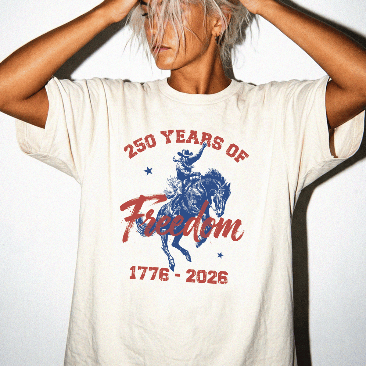 A person wearing a white t-shirt with a graphic design that says "250 YEARS OF Freedom" and "1776-2026".
