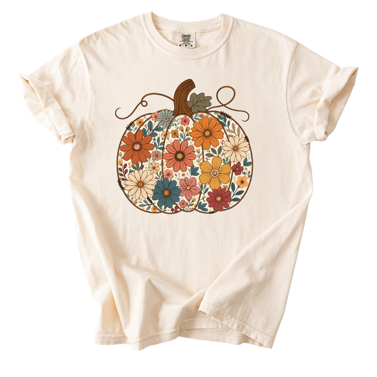 A white t-shirt with a colorful pumpkin graphic featuring a variety of flowers and leaves.