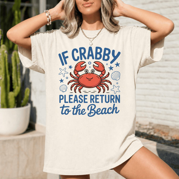 A woman wearing a white t-shirt with a graphic design of a crab and the text "IF CRABBY PLEASE RETURN TO THE BEACH" printed on it.