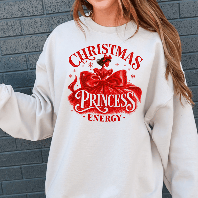 A white sweatshirt with a red graphic design featuring a woman's face and the text "Christmas Princess Energy" printed on it.