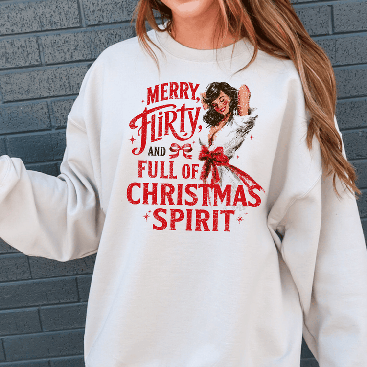 A white sweatshirt with a graphic design featuring a woman with long brown hair and a red bow around her neck, along with the text "Merry, Flirty, and Full of Christmas Spirit" printed on it.
