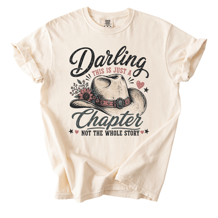 a white t-shirt with a graphic design that includes a cowboy hat and the text "Daring this is just a chapter NOT the whole story".