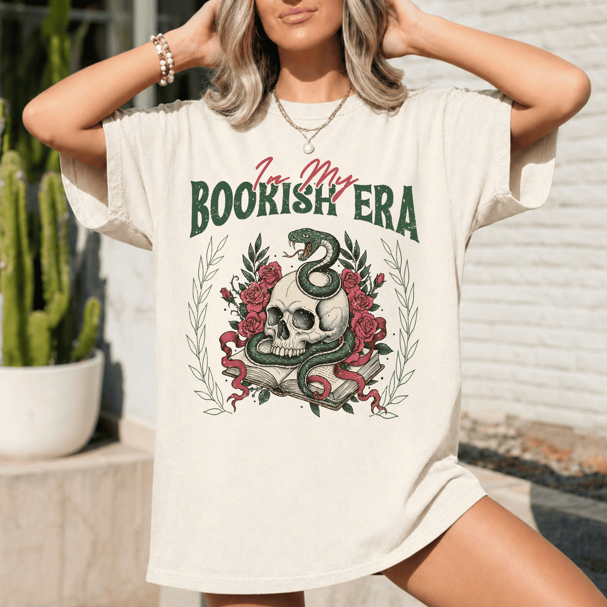 A woman wearing a white t-shirt with a graphic design featuring a skull, roses, and a snake.