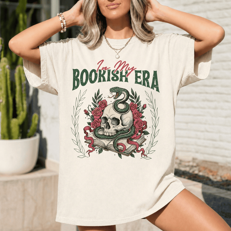 A woman wearing a white t-shirt with a graphic design featuring a skull, roses, and a snake.