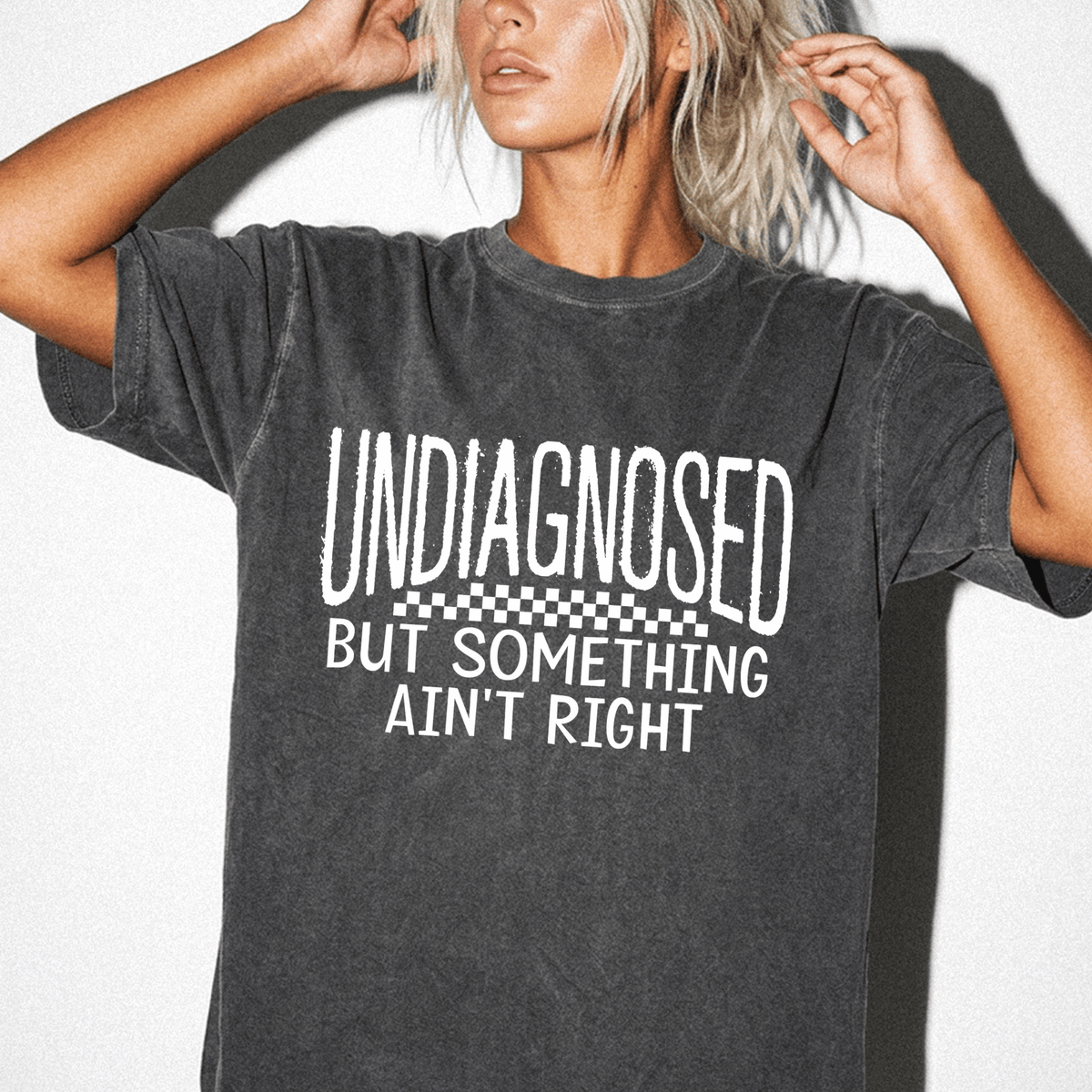 A woman wearing a black t-shirt with the text "UNDIAGNOSED BUT SOMETHING AIN'T RIGHT" printed on it.