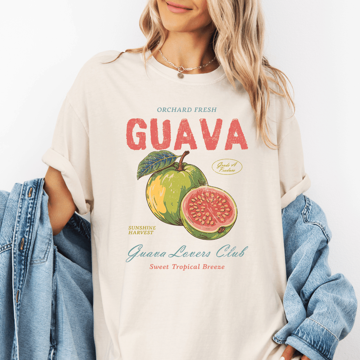 A woman wearing a white t-shirt with a graphic design of a guava fruit and text promoting the Guava Lovers Club.