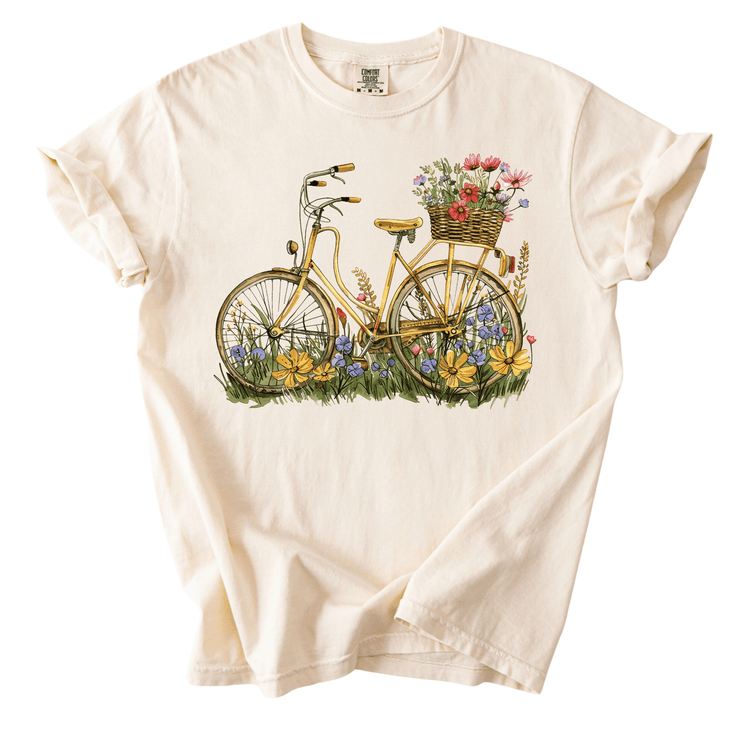 A white t-shirt with a printed design depicting a bicycle with a basket of flowers on the back.