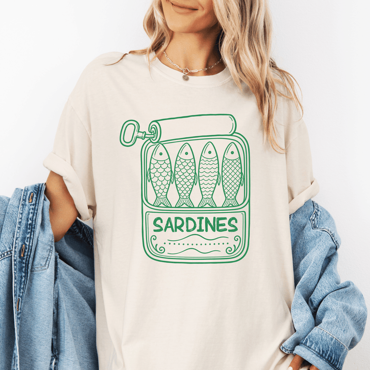 A woman wearing a white t-shirt with a graphic of four fish and the word "Sardines" printed on it.
