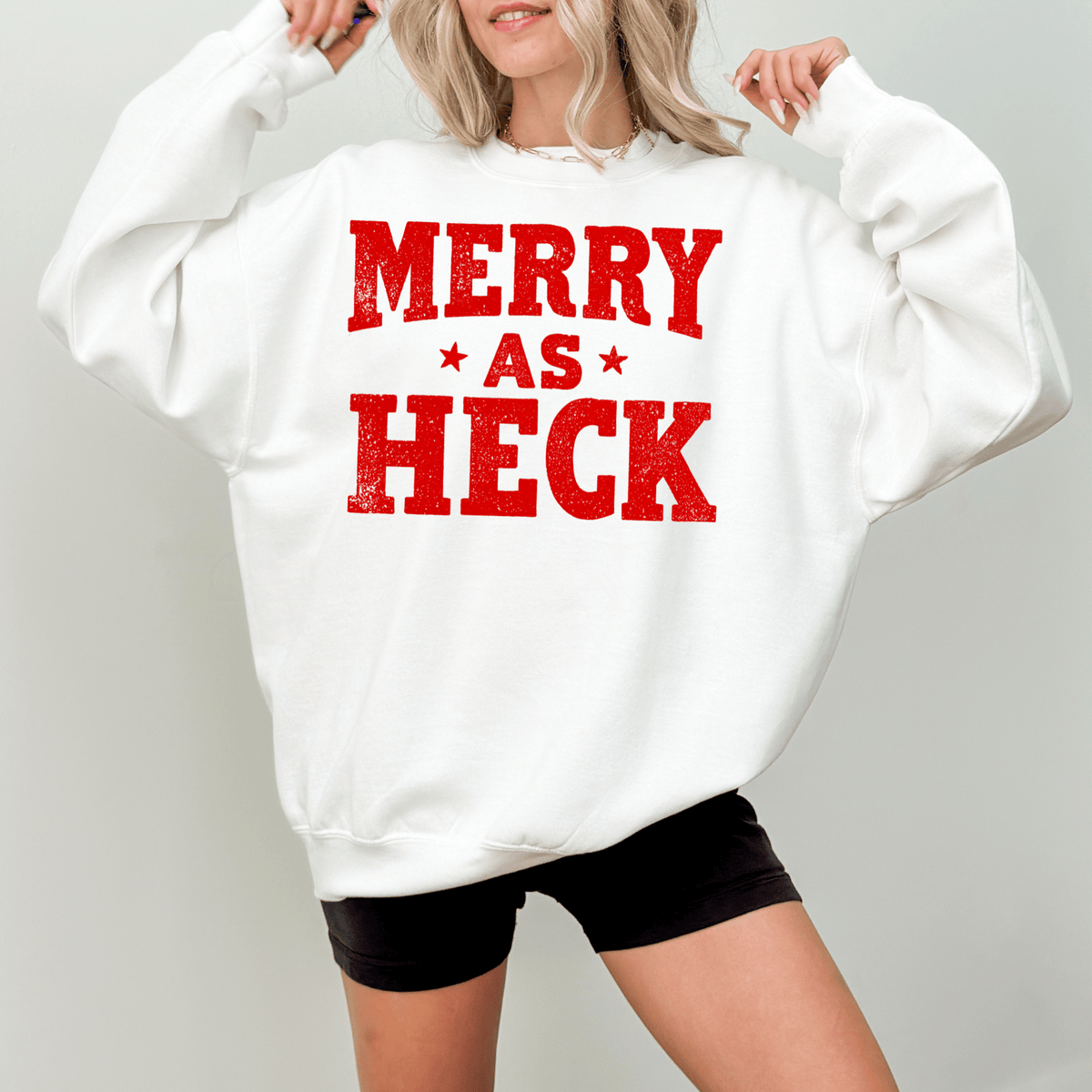 A woman wearing a white sweatshirt with the text "MERRY AS HEK" printed on it.