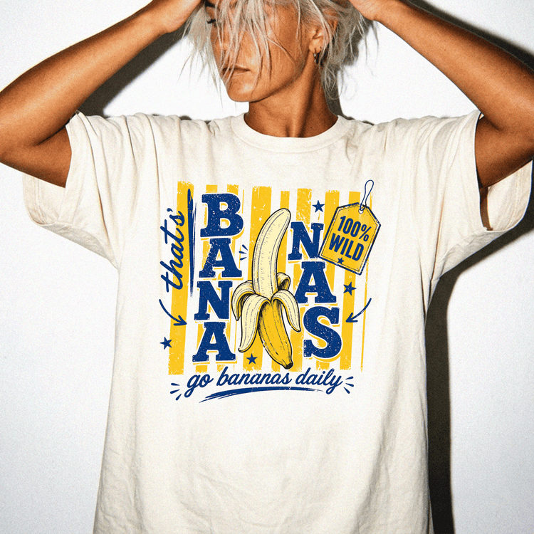 A person wearing a white t-shirt with a graphic design featuring a banana and the text "go bananas daily" printed on it.