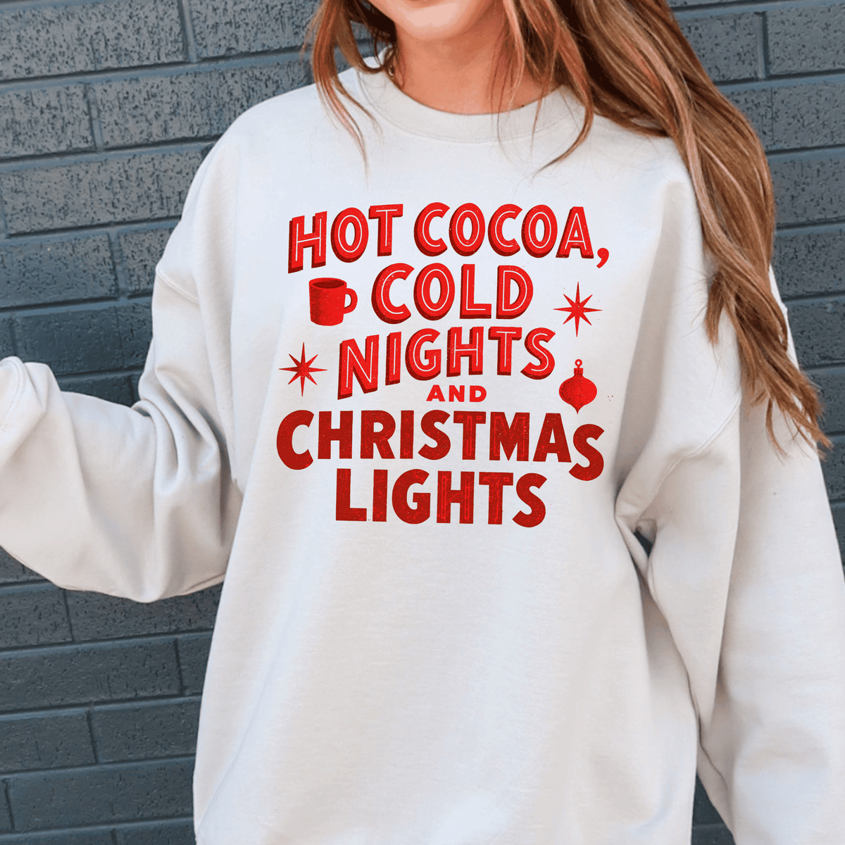 A white sweatshirt with red text that says "HOT COCOA, COLD NIGHTS AND CHRISTMAS LIGHTS".