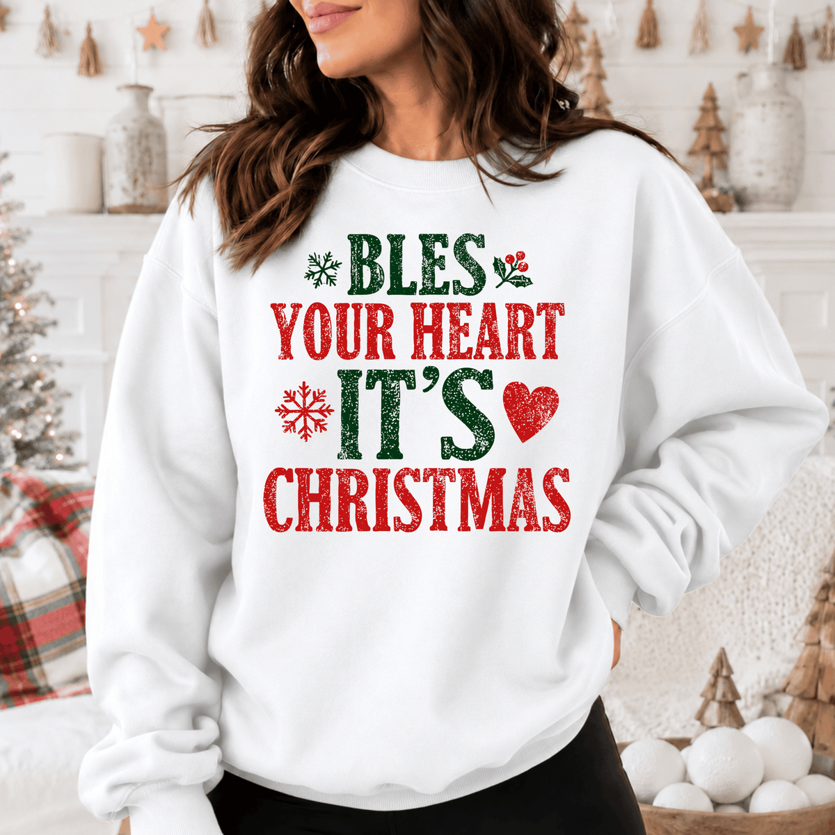 A woman wearing a white sweatshirt with a Christmas-themed design, including text and graphics.