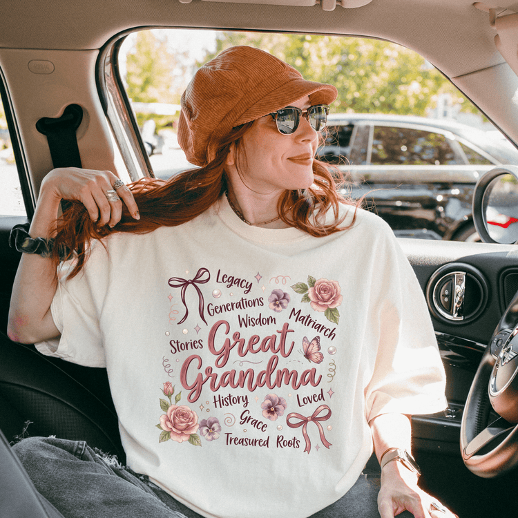 A woman wearing a white t-shirt with text and a bow on it, sitting in a car and smiling.