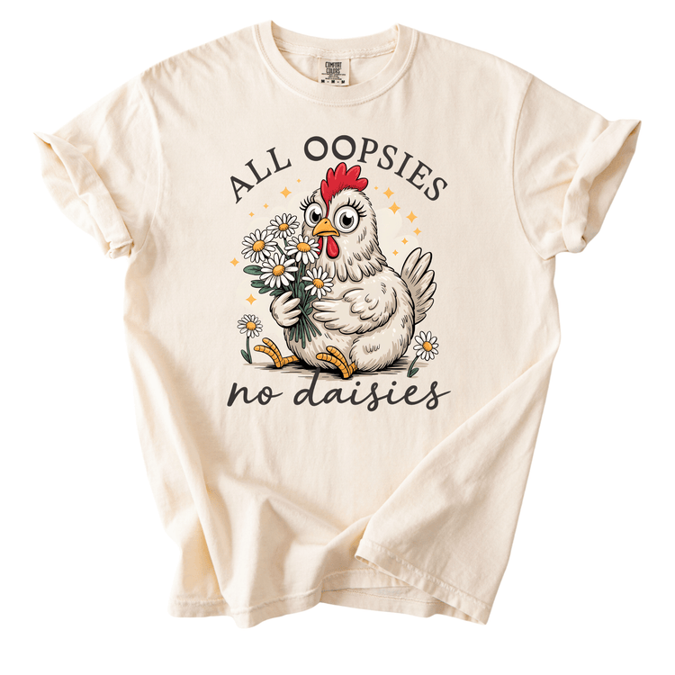 A white t-shirt with a graphic design featuring a cartoon chicken holding flowers and the text "ALL OOPSIES no daisies".
