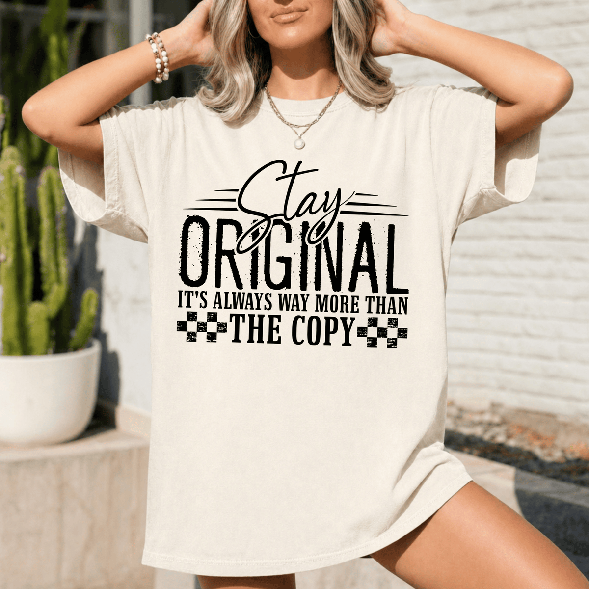 A woman wearing a white t-shirt with a printed message that says "Stay original, it's always way more than the copy".