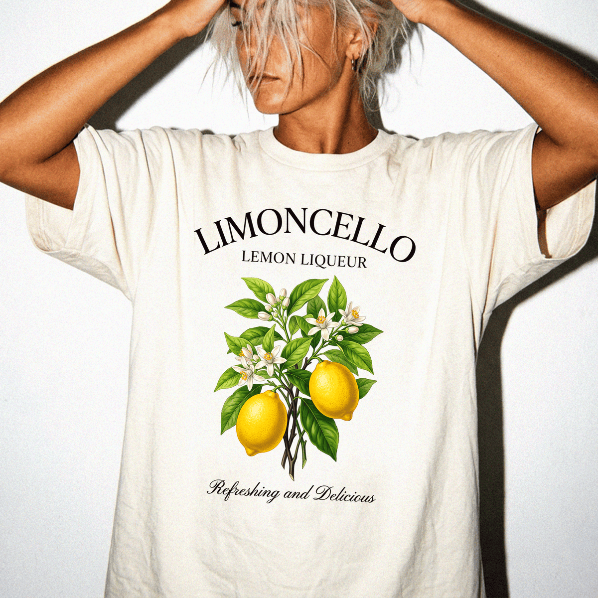 A person wearing a white t-shirt with a graphic design of lemons and leaves, along with the text "LIMONCELLO LEMON LIQUEUR" and "Refreshing and Delicious".