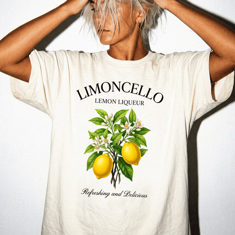 A person wearing a white t-shirt with a graphic design of lemons and leaves, along with the text "LIMONCELLO LEMON LIQUEUR" and "Refreshing and Delicious".