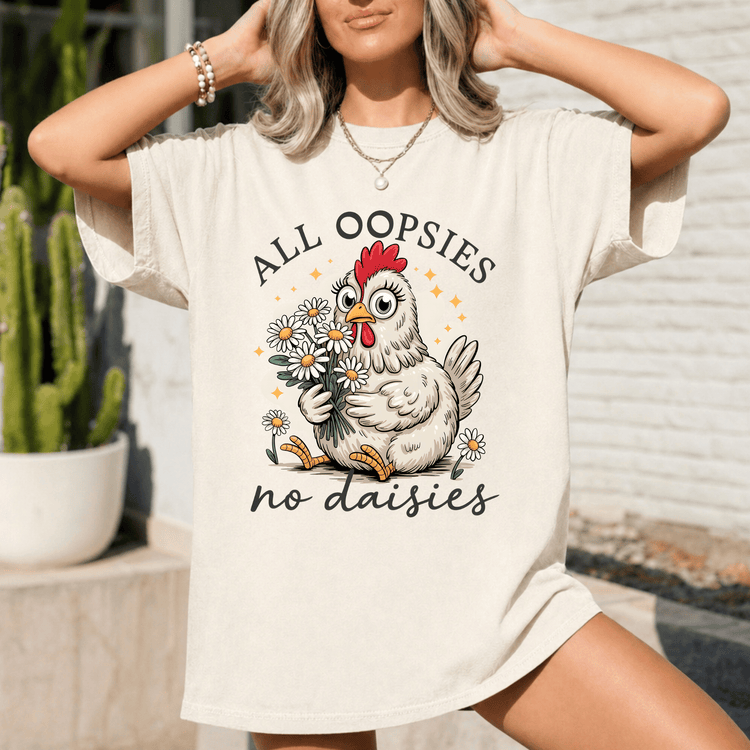 A woman wearing a white t-shirt with a graphic design of a chicken holding flowers and the text "All Oopsies no daisies".