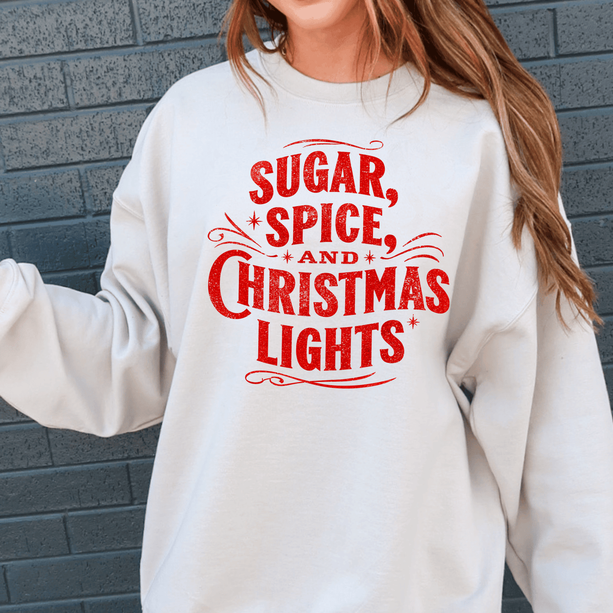 A white sweatshirt with red text that says "SUGAR, SPICE, AND CHRISTMAS LIGHTS".