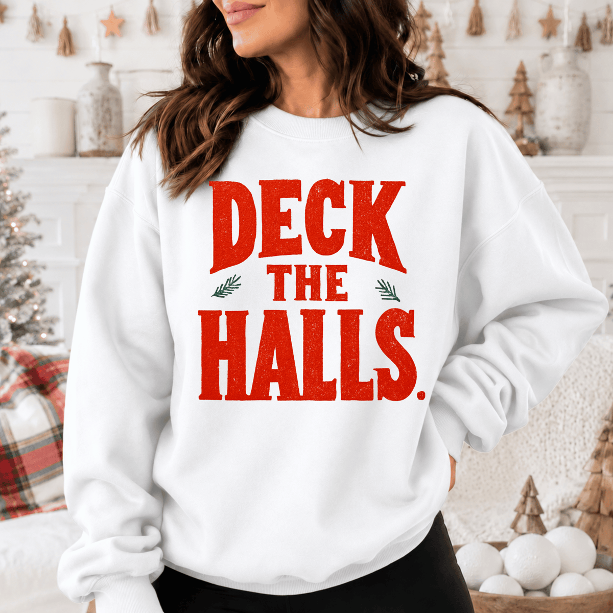 A woman wearing a white sweatshirt with the text "DECK THE HALLS" printed on it.