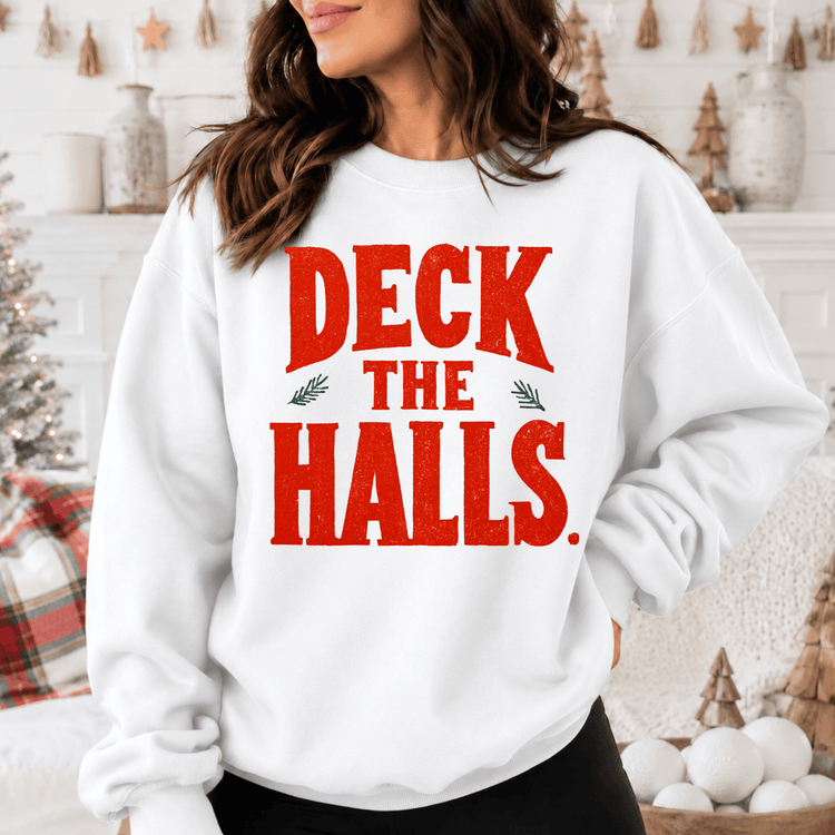 A woman wearing a white sweatshirt with the text "DECK THE HALLS" printed on it.