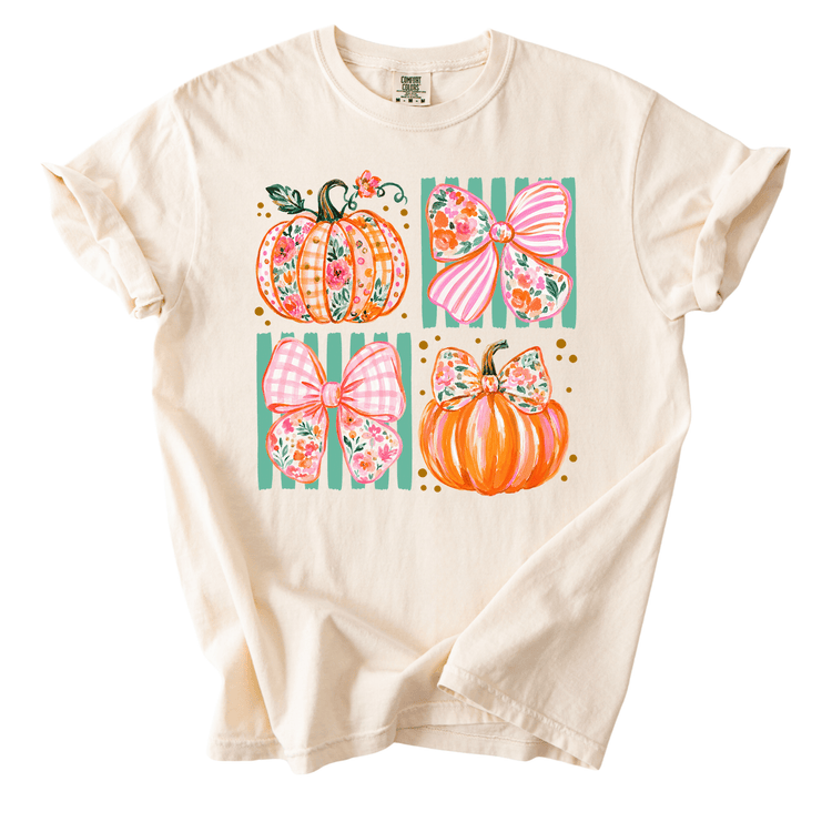 A white t-shirt with a graphic design featuring four colorful pumpkins and bows.