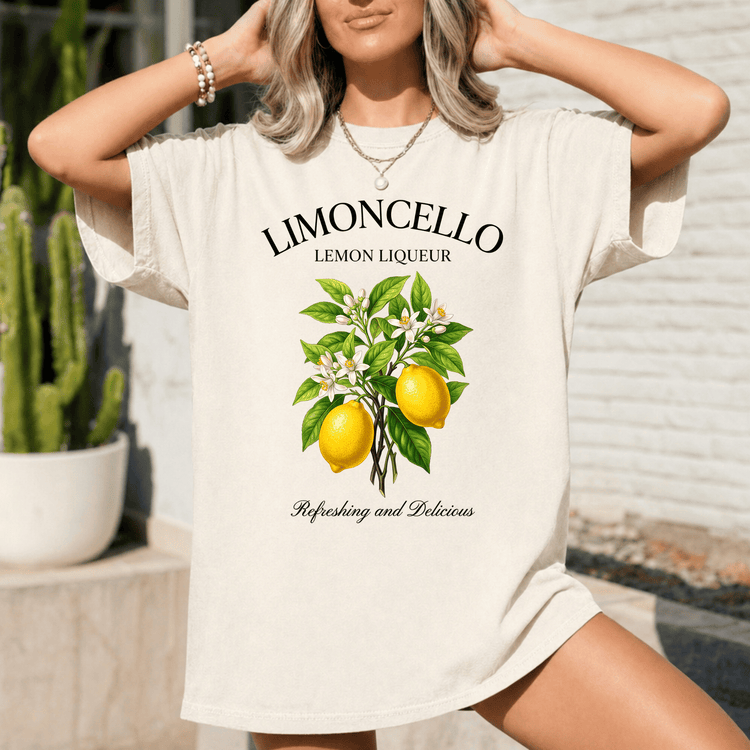 A woman wearing a white t-shirt with a graphic of a lemon tree and the text "LIMONCELLO LEMON LIQUEUR" printed on it.