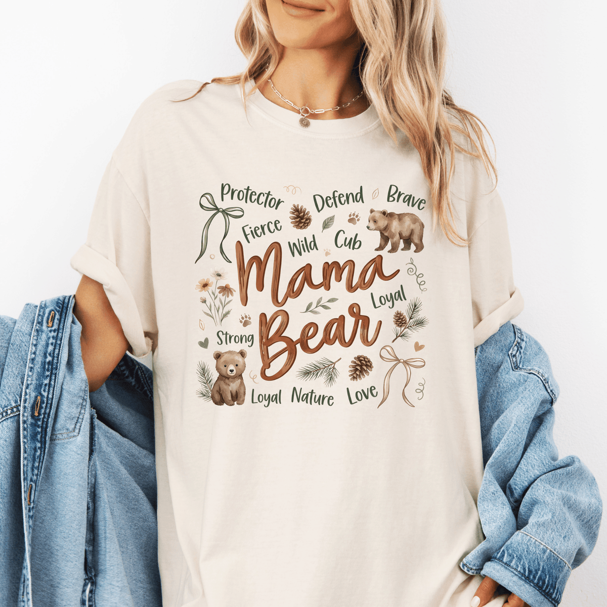 A woman wearing a white t-shirt with a graphic design featuring a bear and the words "Mama Bear" printed on it.