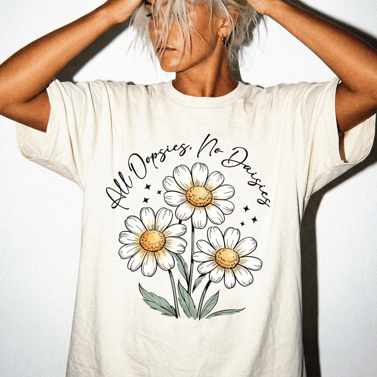 A person wearing a white t-shirt with a graphic design of three white daisies and green leaves.