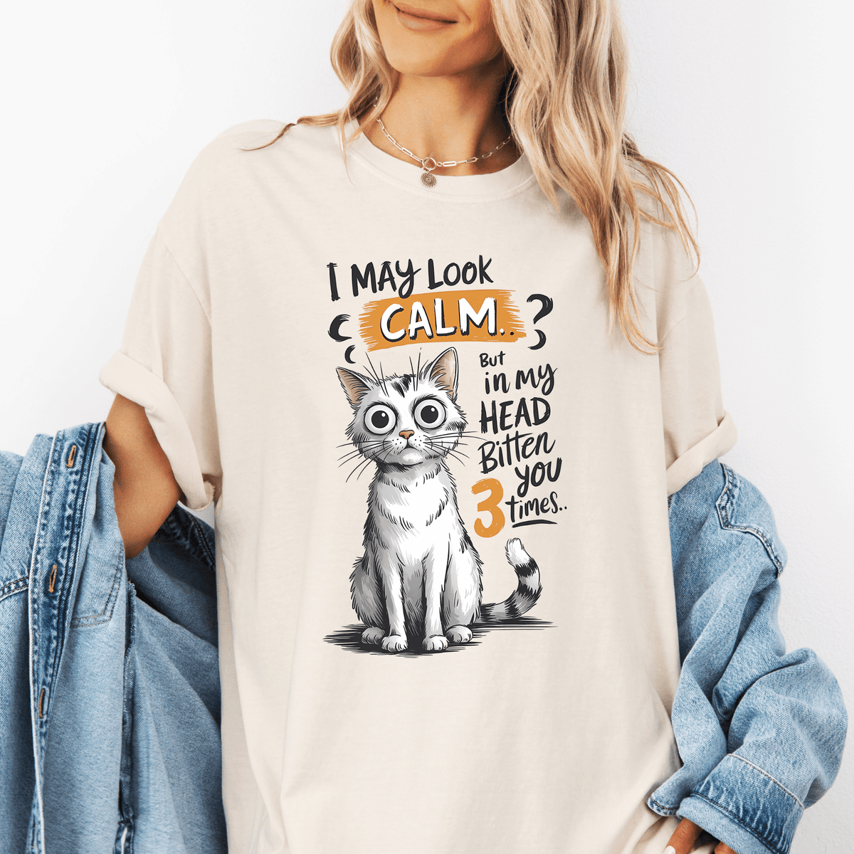 A woman wearing a white t-shirt with a graphic of a cat and text that says "I may look calm, but in my head bitten you 3 times".