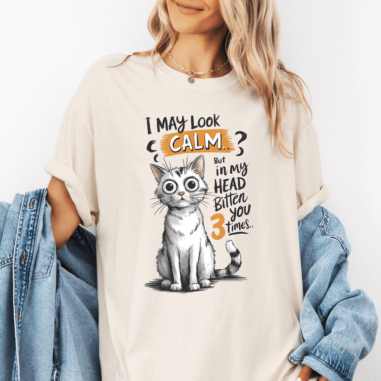 A woman wearing a white t-shirt with a graphic of a cat and text that says "I may look calm, but in my head bitten you 3 times".