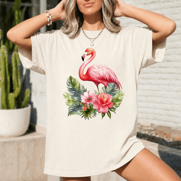 A woman wearing a white t-shirt with a pink flamingo and tropical flowers printed on it.