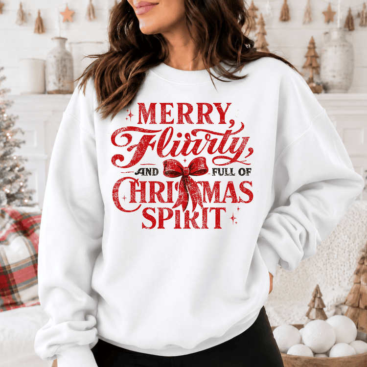 A woman wearing a white sweatshirt with a red and white text design that says "MERRY FLIRTY AND FULL OF CHRISTMAS SPIRIT".