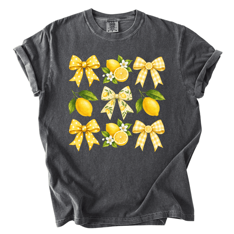 A gray t-shirt with a graphic design featuring yellow polka dots, lemons, and bows.