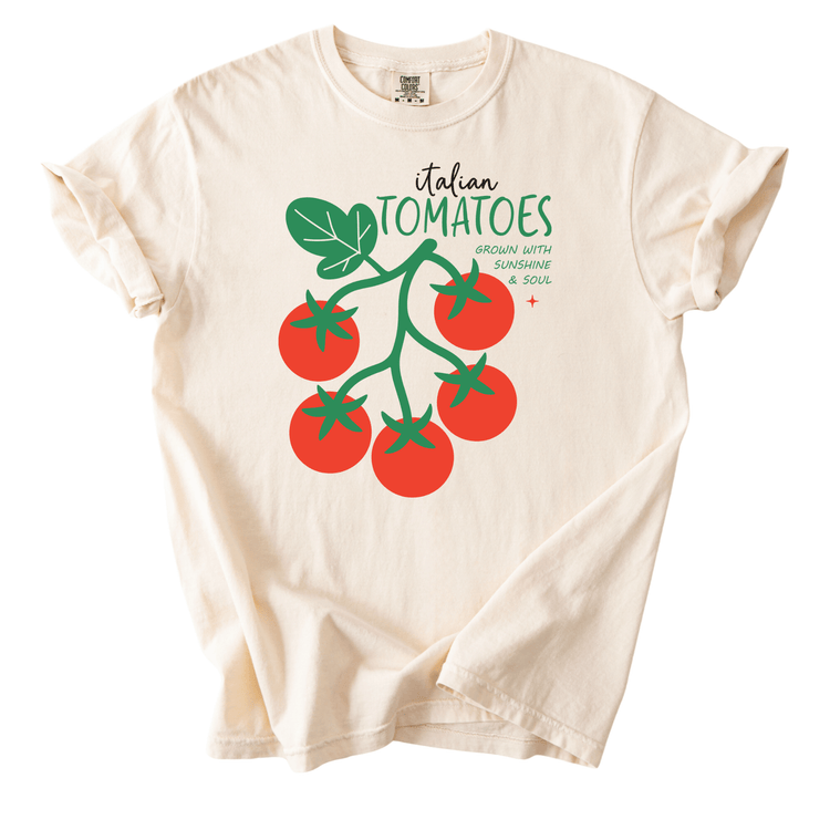 A white t-shirt with a graphic design of a bunch of red tomatoes and green leaves.