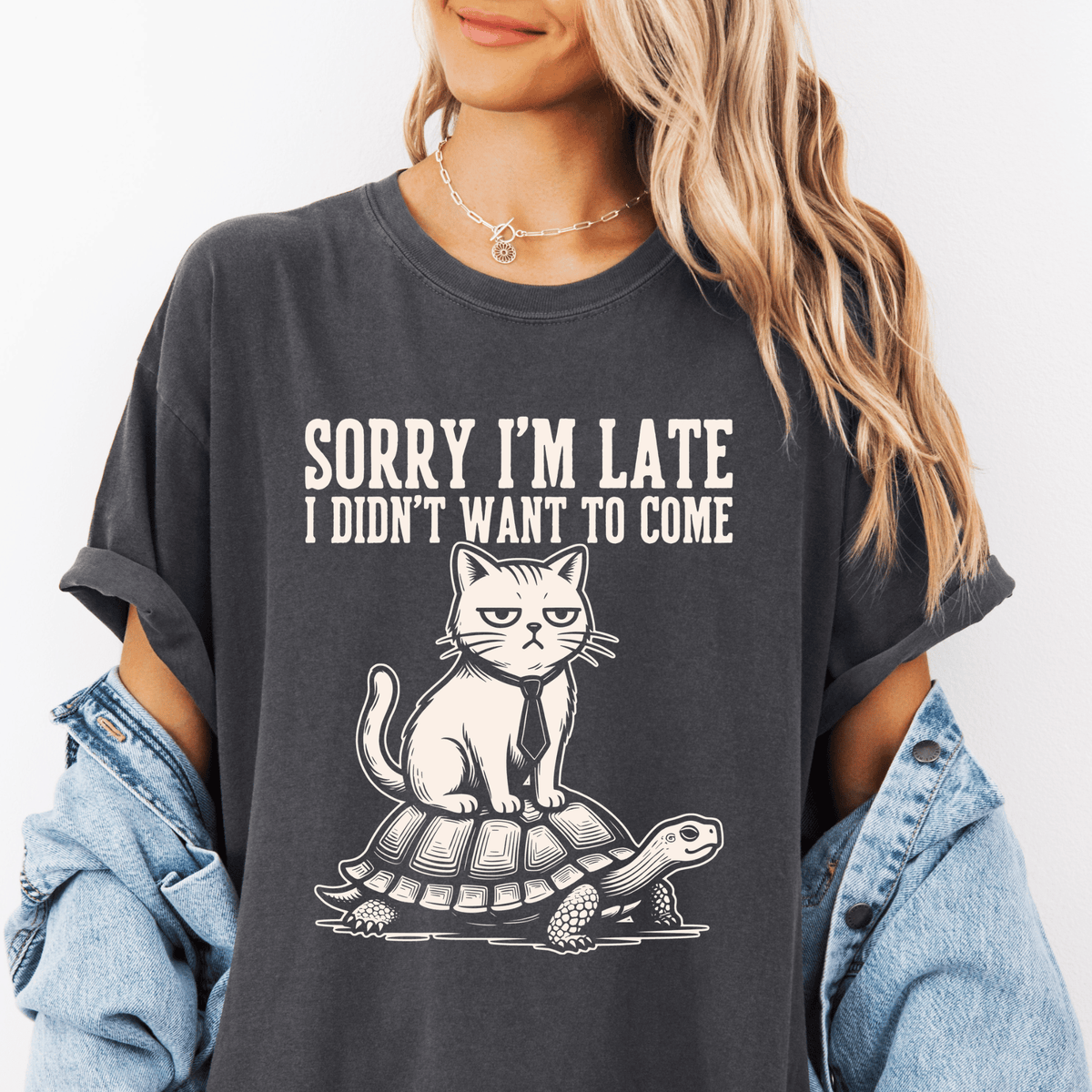 A woman wearing a gray t-shirt with a graphic design of a cat sitting on a turtle.