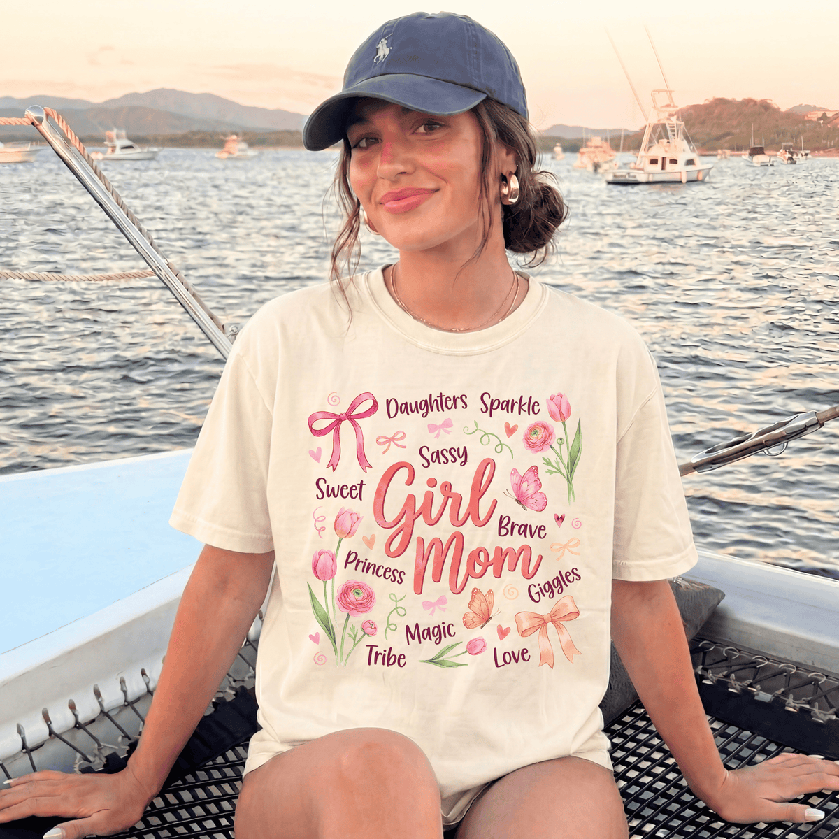A woman wearing a white t-shirt with a printed design of flowers and text, sitting on a boat in the water.